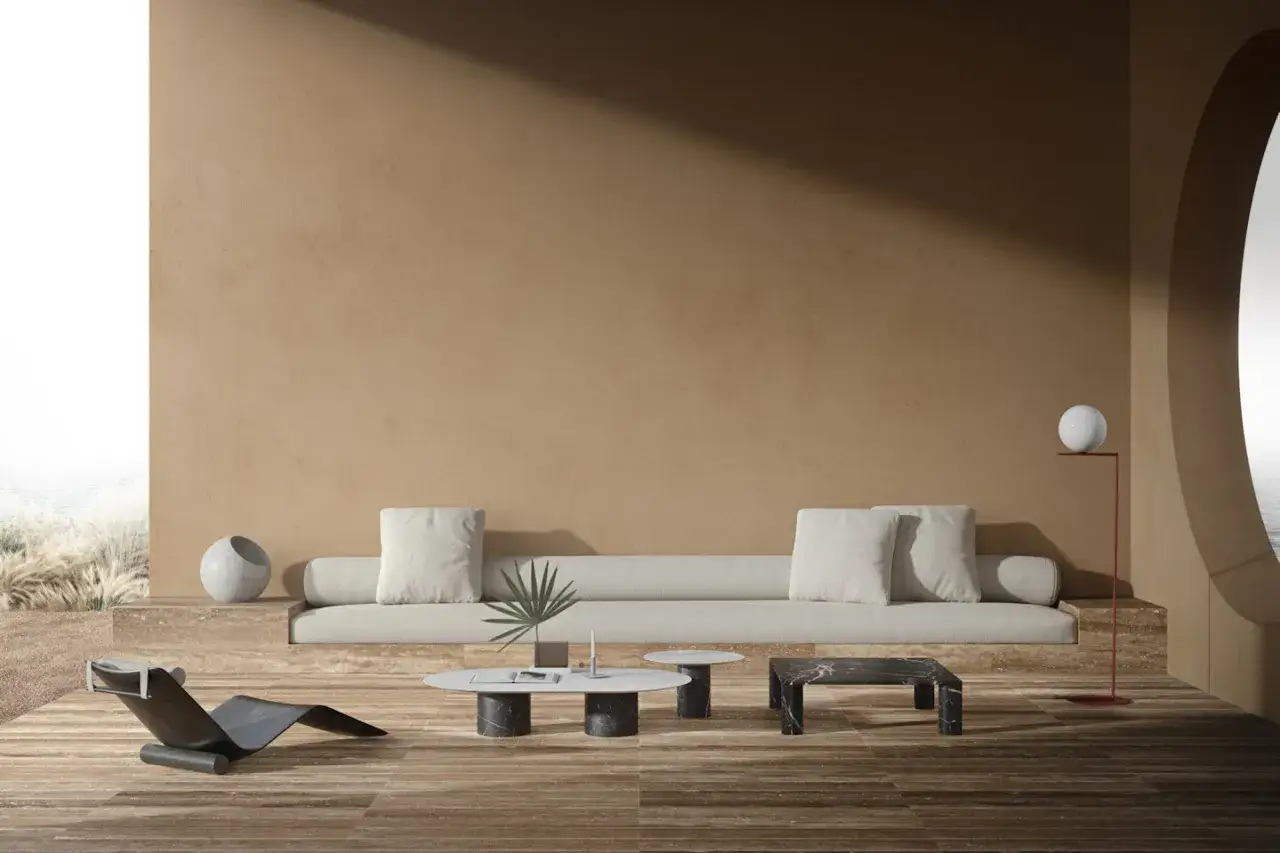 Salotto minimalista con divano lungo, poltrona di design e tavolini in marmo. Una casa di design con vista sul mare.