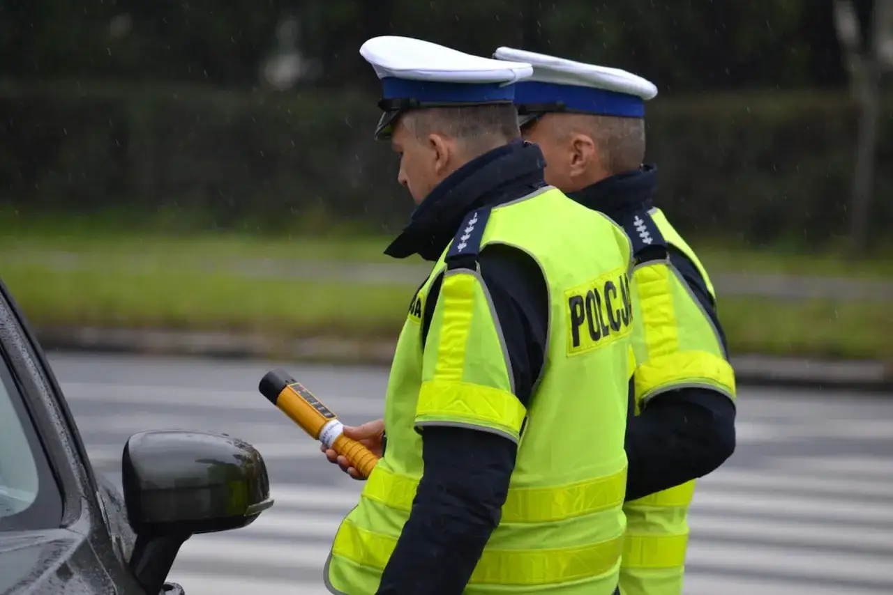 Policjant w kamizelce odblaskowej trzyma alkomat. Czy można odmówić badania alkomatem? Pytanie to nurtuje wielu kierowców.
