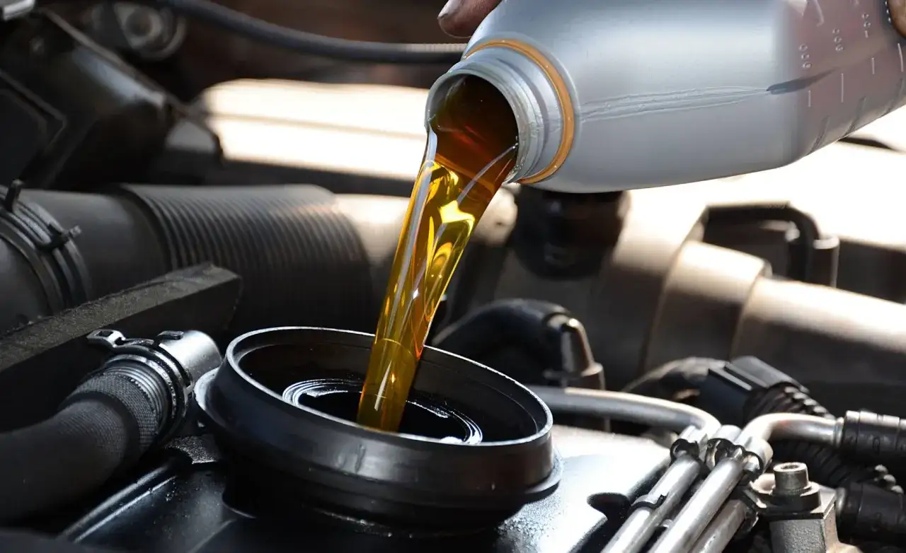 Vertiendo aceite nuevo en el motor de un coche. Es importante mezclar aceites coche de calidad para su buen funcionamiento.