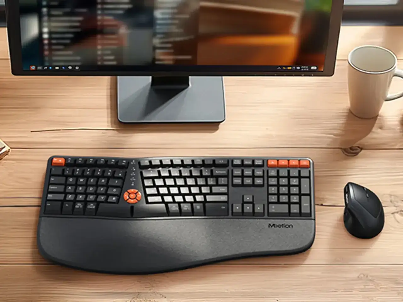 Un teclado ergon&oacute;mico y un rat&oacute;n negro son ejemplos de qu&eacute; son los perif&eacute;ricos de un ordenador, junto a un monitor y una taza.