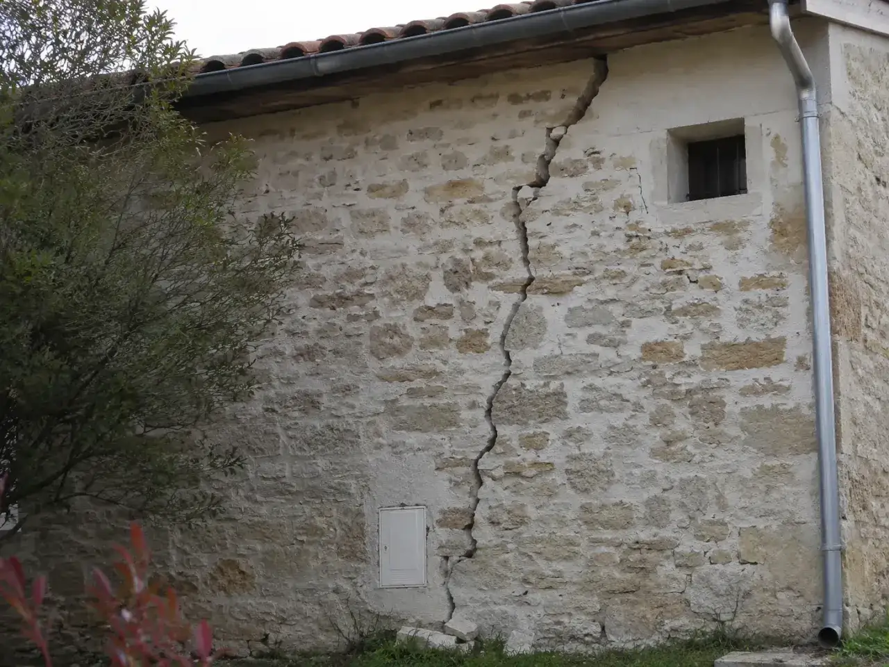 Une fissure béante traverse le mur de pierre d'une vieille maison. On dirait que cette maison qui craque toujours au même endroit raconte une histoire de temps et de mouvements.