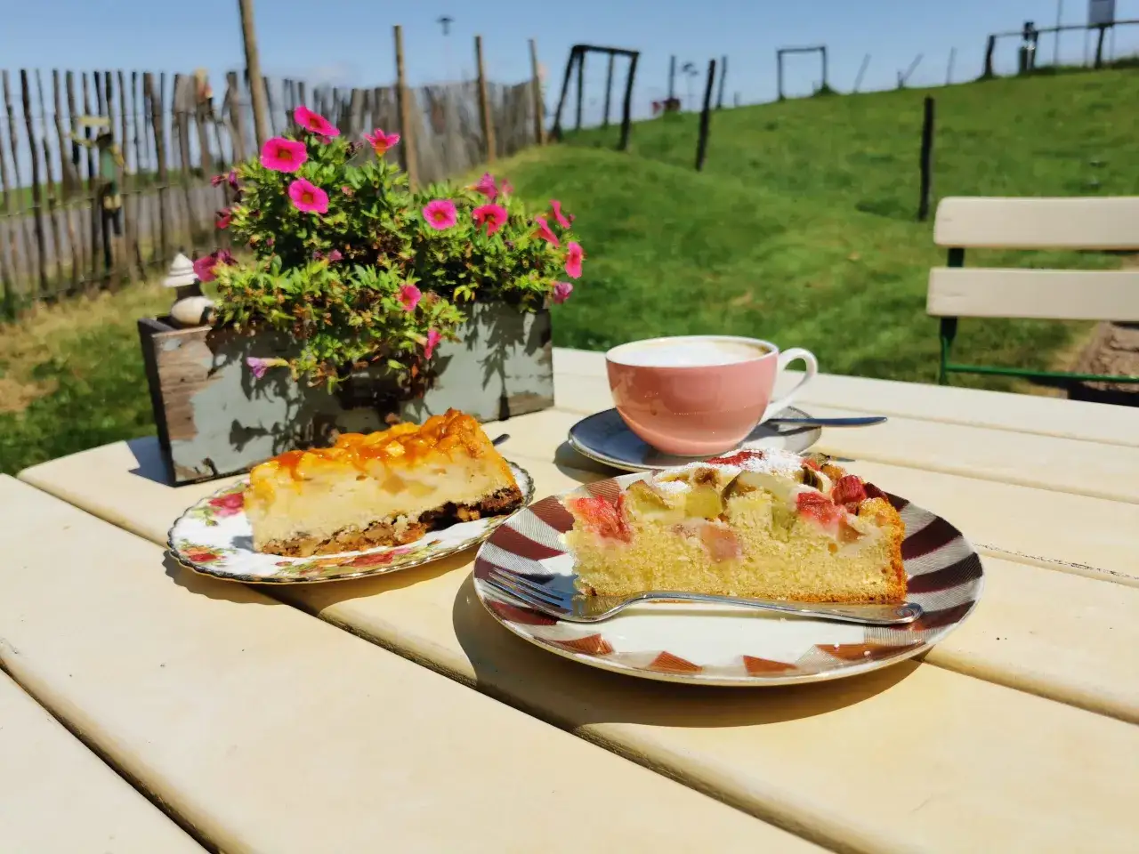 Zwei Stücke Kuchen und ein Kaffee auf einem Tisch im Freien. Ein Genuss im Kuchen Cafe.