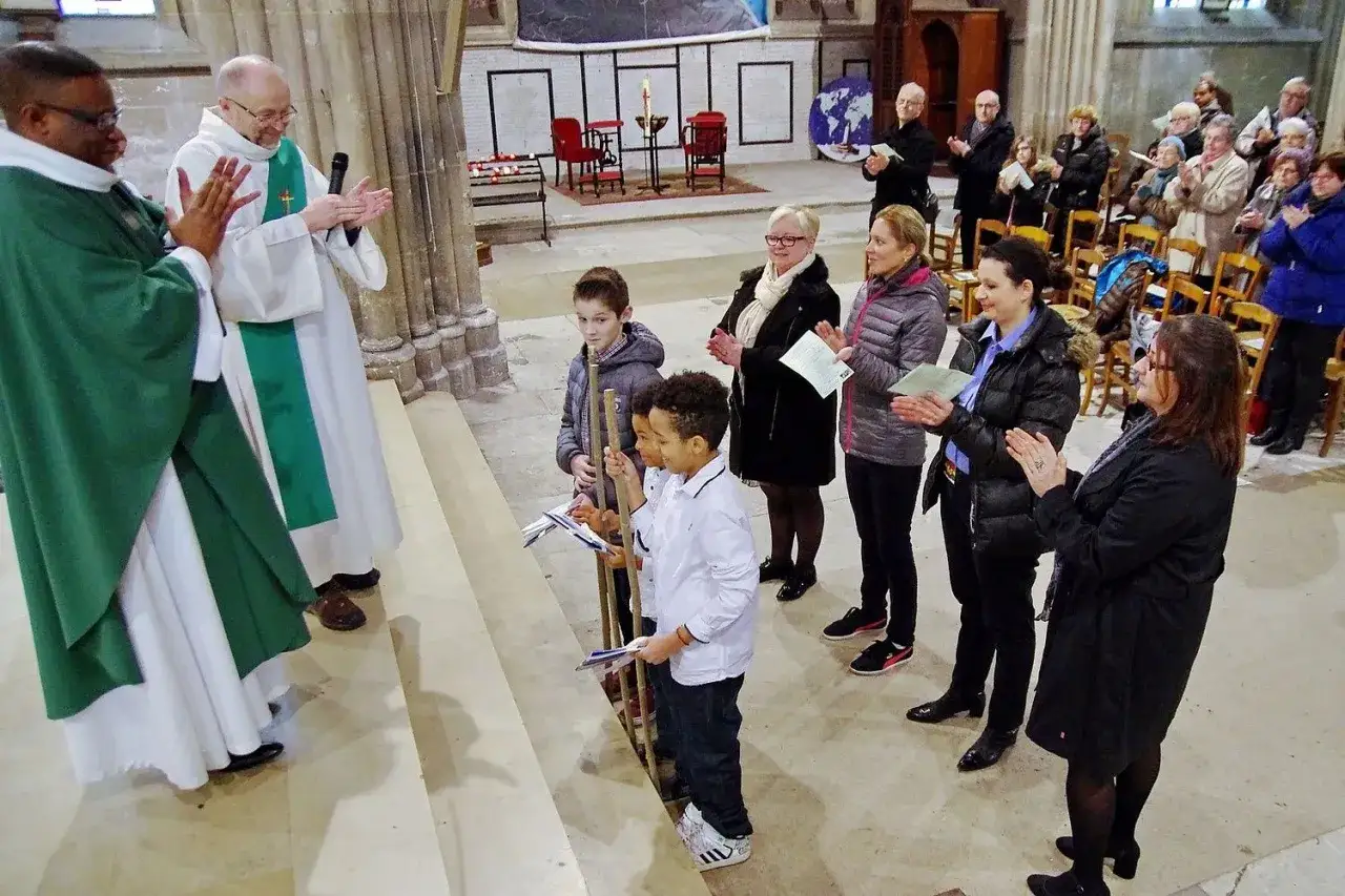 Quel jour pour un baptême ! Des enfants se tiennent prêts, entourés de leurs familles et de deux prêtres dans une église.