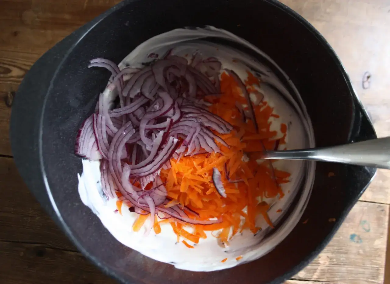 En sk&aring;l med kr&auml;mig majonn&auml;s, strimlad morot och r&ouml;dl&ouml;k. Ingredienser f&ouml;r godaste coleslaw.