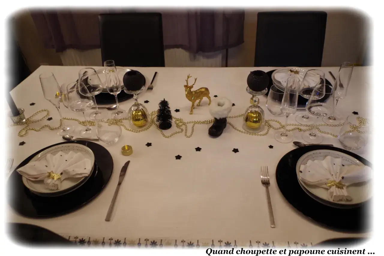 Table dress&eacute;e pour un r&eacute;veillon festif, avec des verres, des boules dor&eacute;es et une figurine de renne. Un th&egrave;me pour nouvel an &eacute;l&eacute;gant et scintillant.