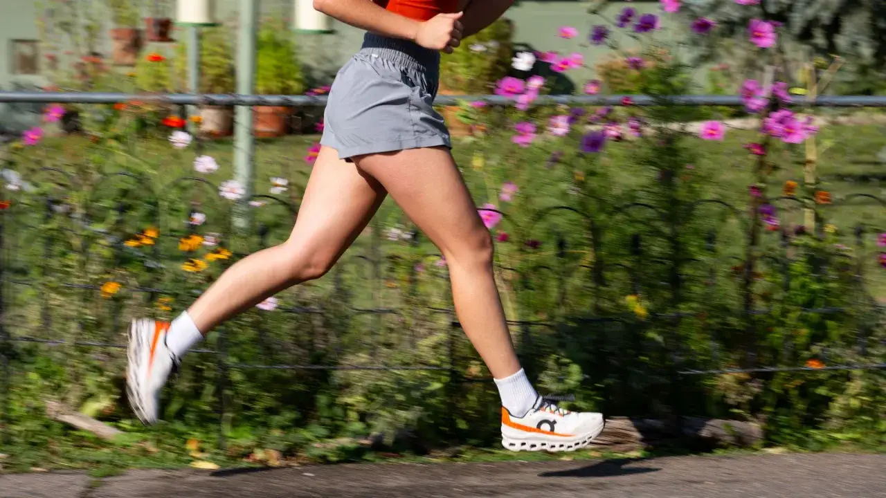 L&auml;uferin mit kurzen Hosen und wei&szlig;en Socken, deren **beine jucken beim laufen** durch den bl&uuml;henden Garten.