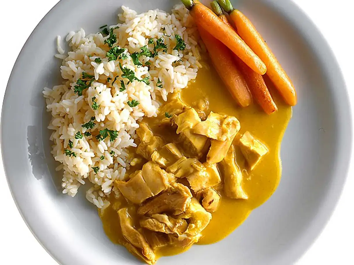 En portion kyckling och ris med currysås och små morötter.