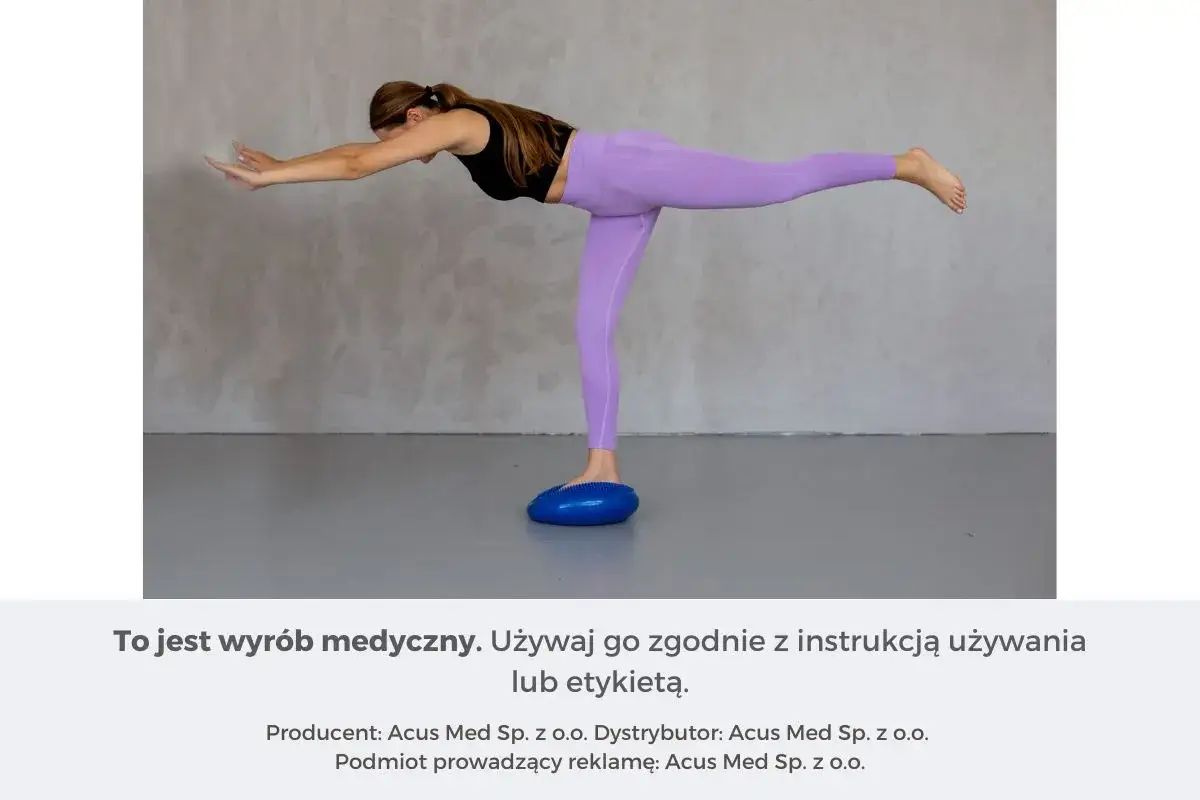 Kobieta wykonuje ćwiczenia propriocepcji na niebieskiej poduszce balansującej, unosząc jedną nogę i wyciągając ręce do przodu.