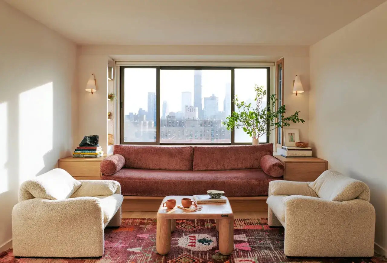 Acogedor sal&oacute;n de 18 metros cuadrados con sof&aacute; rosa, sillones blancos y vistas a la ciudad.