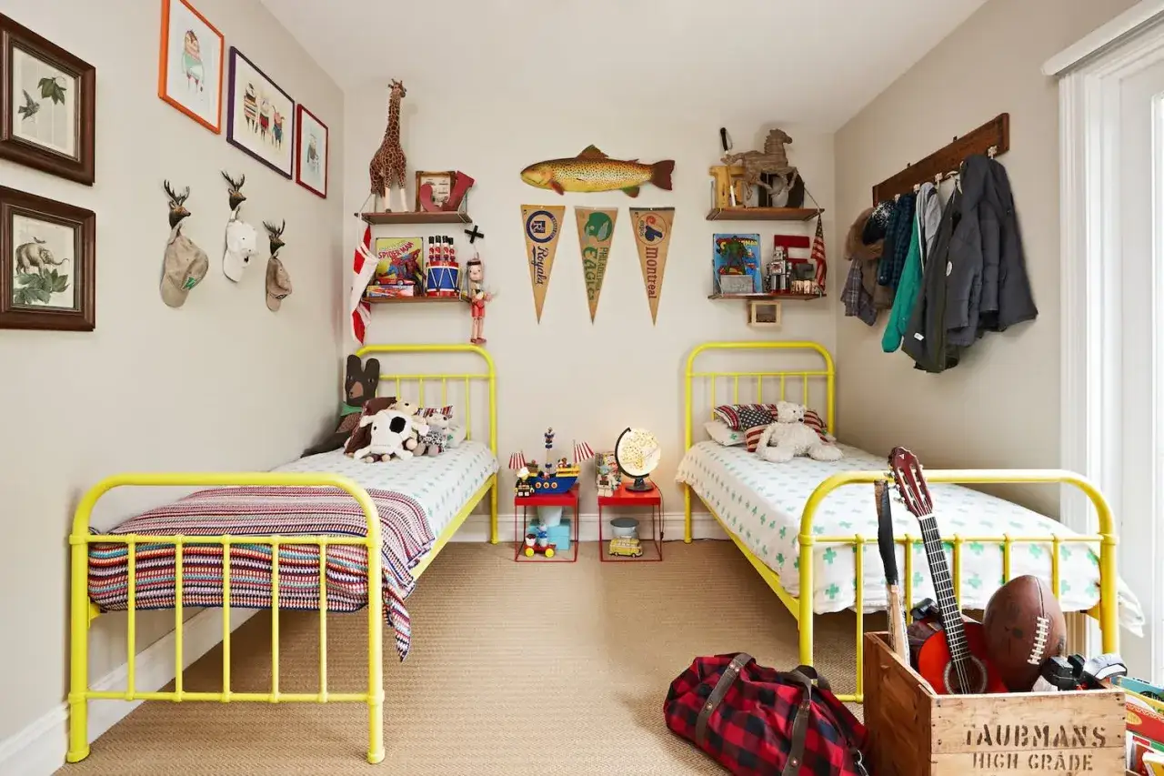 Zwei gelbe Betten in einem Kinderzimmer, das viele Ideen für ein geschwister zimmer teilen bietet. Spielzeug, Bilder und Sportartikel schmücken den Raum.