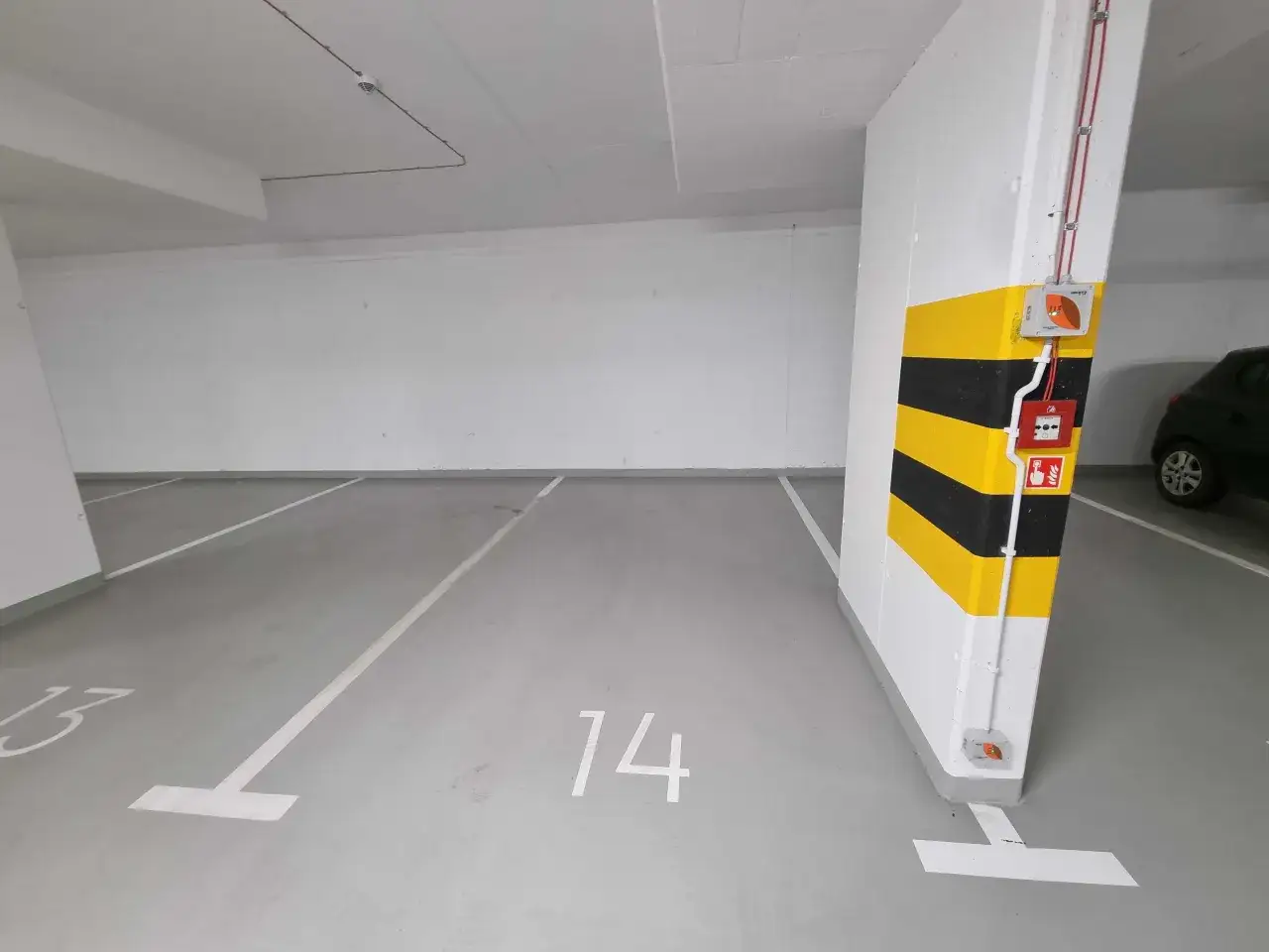 Puste miejsca parkingowe pod blokiem, numerowane 13 i 14. Zastanawiasz się, ile kosztuje miejsce parkingowe pod blokiem?