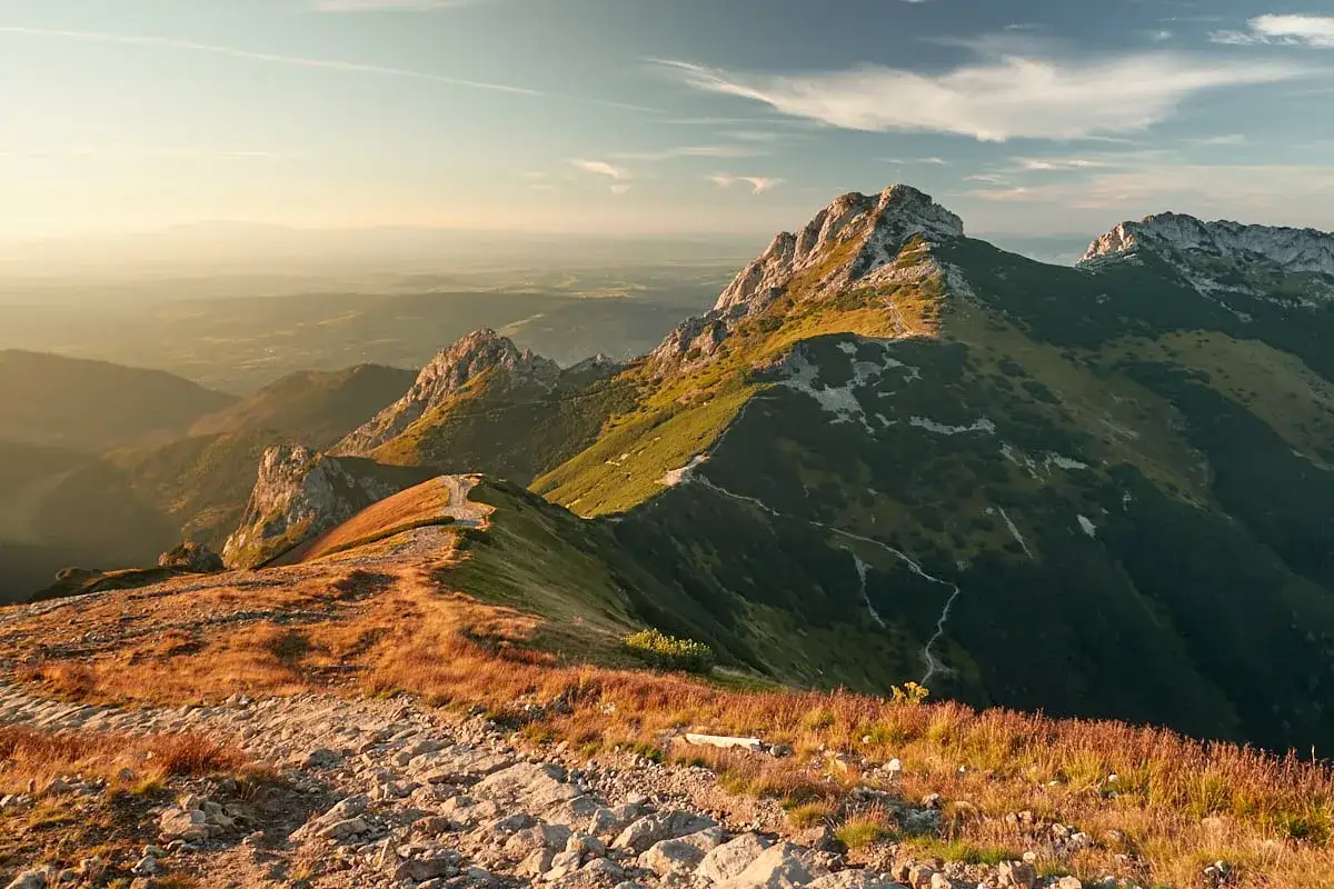 Malownicza trasa na Giewont o zachodzie słońca. Kamienista ścieżka wije się pośród traw i skalistych zboczy.