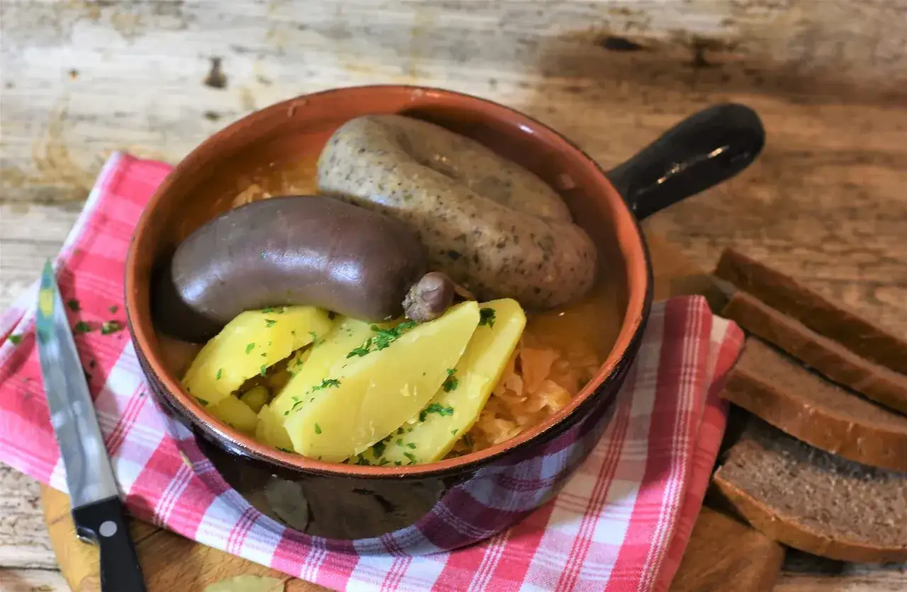 Tradycyjna kaszanka – przepis dziadka. Aromatyczna kaszanka z ziemniakami i kapustą, podana w glinianym naczyniu.