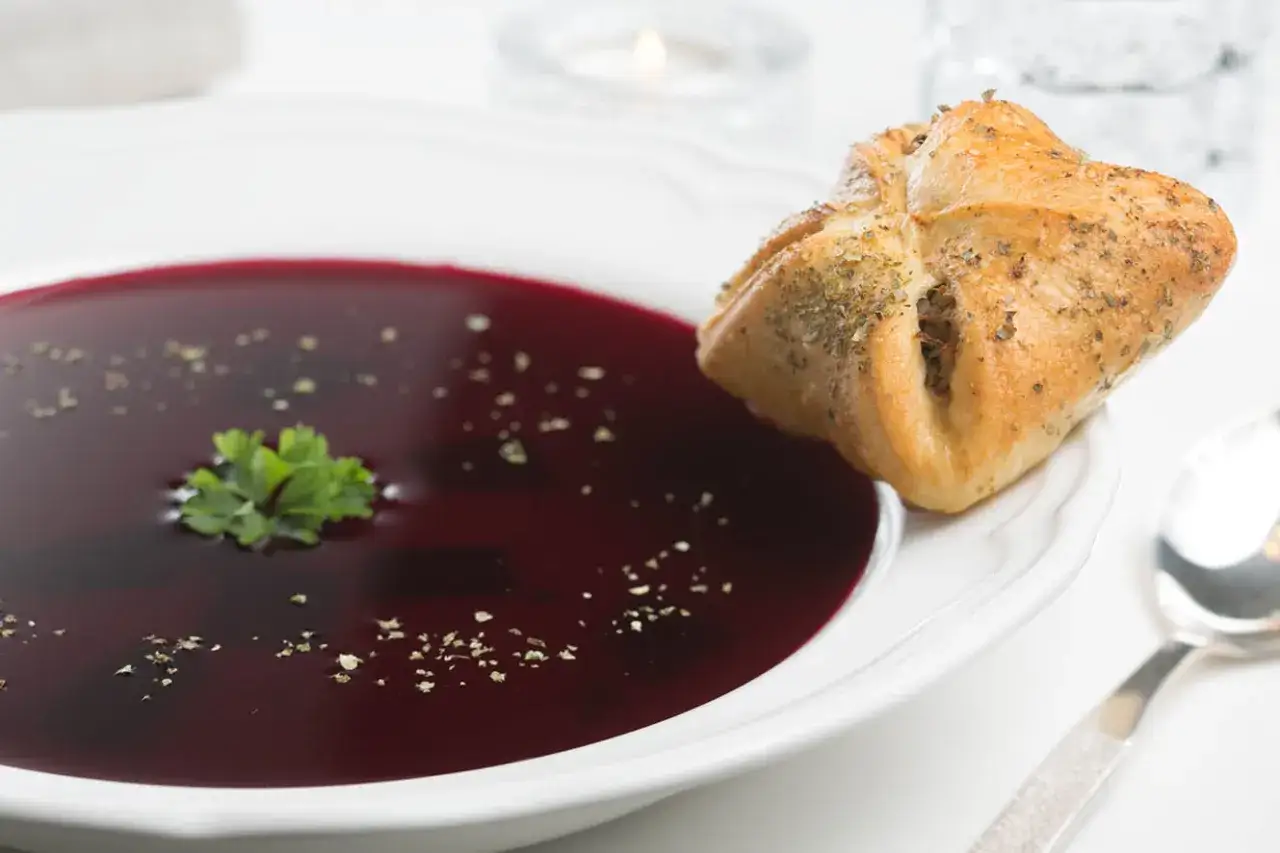 Aromaticzny barszcz z pasztecikiem, ozdobiony natką pietruszki i przyprawami. Idealny na chłodne dni.
