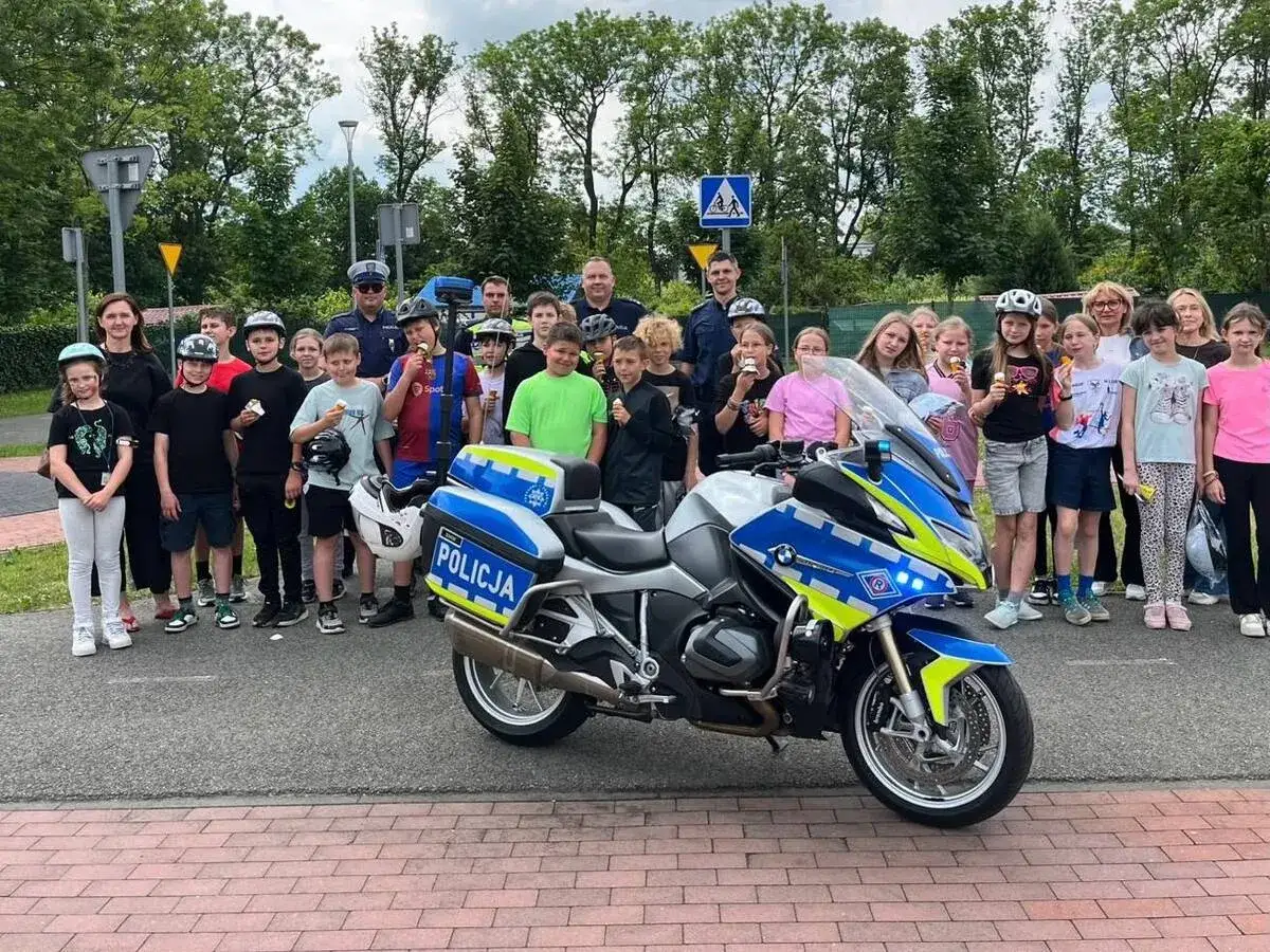 Dzieci z lodami pozują z policjantami i motocyklem. Dowiedz się, ile kosztuje karta rowerowa na policji.