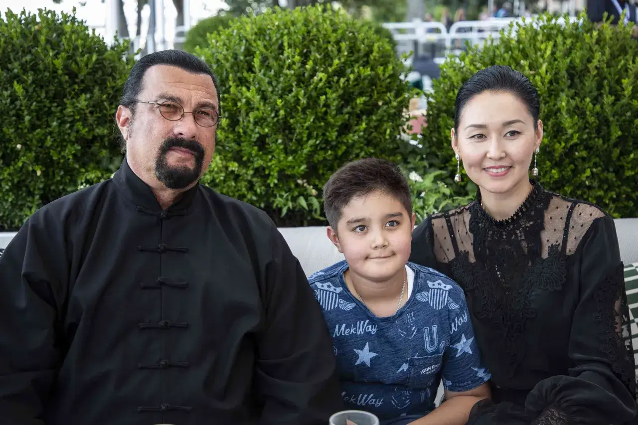 Steven Seagal z żoną i synem. Aktor w tradycyjnym stroju, jego żona w eleganckiej czarnej sukni.