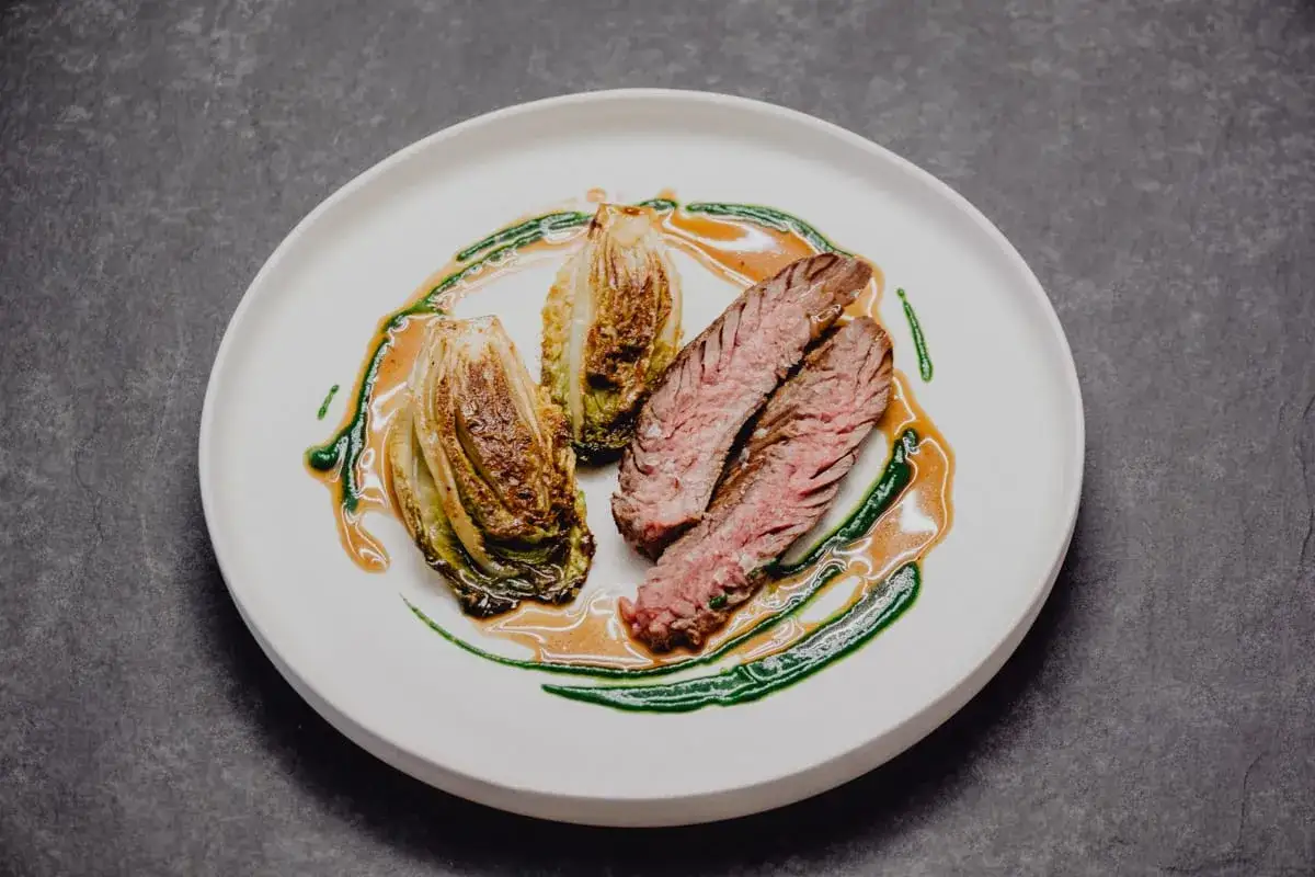 Délicieux onglet de veau tranché, servi avec des endives braisées et nappé d'une sauce onctueuse.