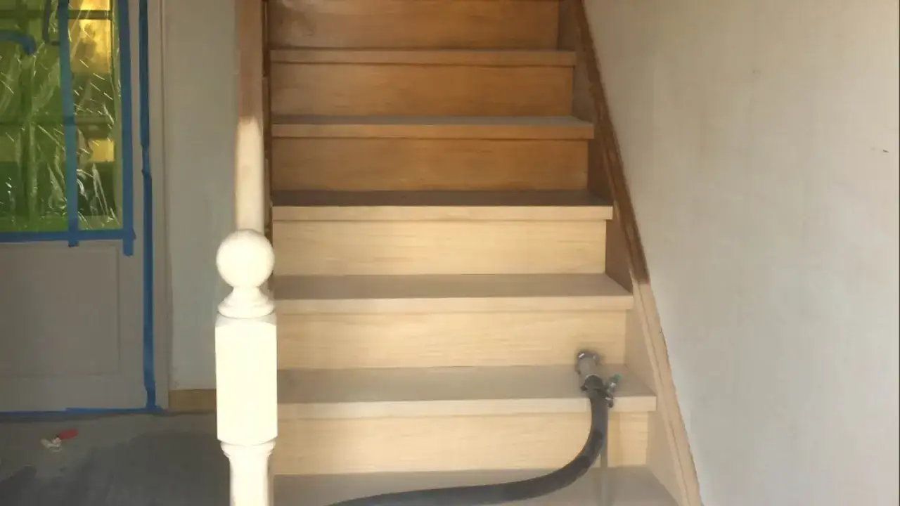 Een trap wordt luchtgegommen, een methode om hout te reinigen en te verfrissen. De bovenste treden zijn donkerder, de onderste lichter.