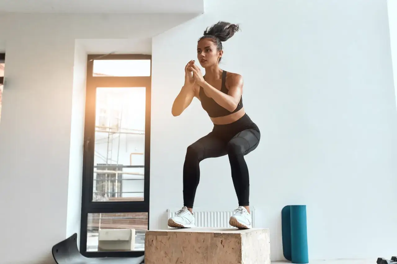Kobieta wykonuje przysiad na skrzyni. Czy crossfit jest zdrowy? Intensywny trening buduje siłę i wytrzymałość.