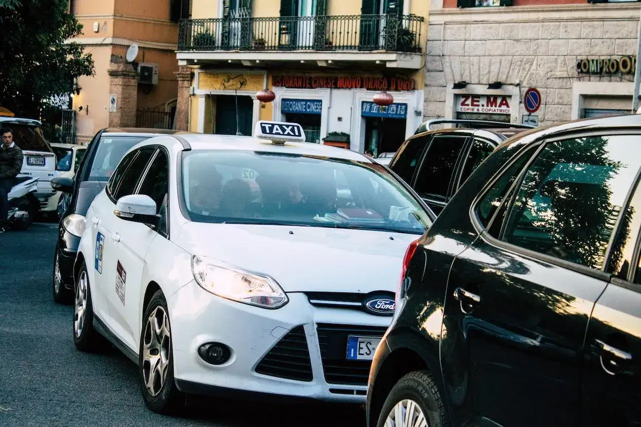 Un taxi bianco in fila con altre auto in una strada cittadina. Chissà quanto guadagna un tassista con questo traffico.