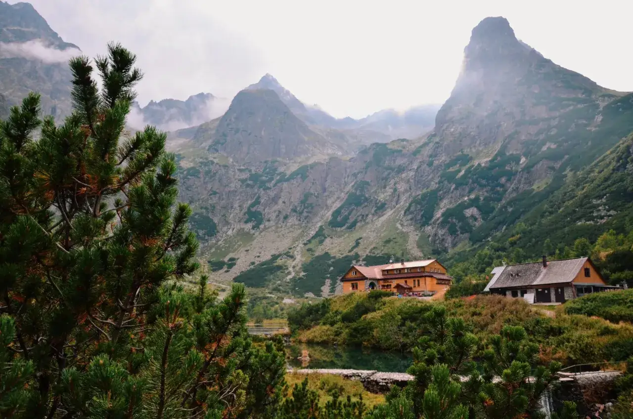Malownicze Słowackie Tatry. Dwa schroniska w górskiej dolinie, otoczone zielenią i skalistymi szczytami.