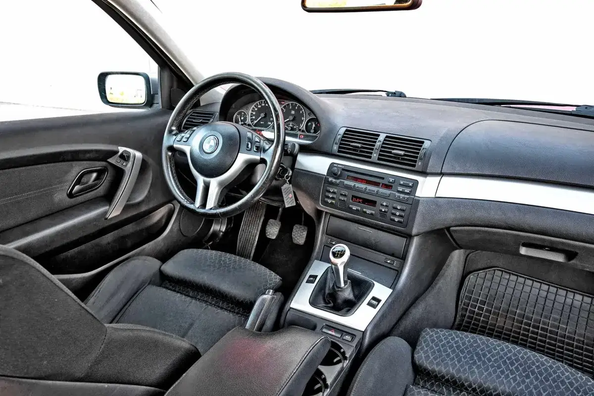 Wnętrze BMW E46 Coupe M Pakiet: czarna tapicerka, sportowa kierownica, manualna skrzynia biegów i radio.