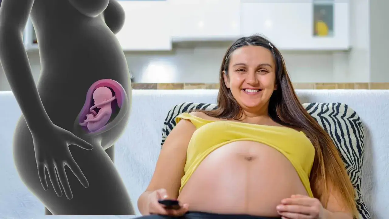 En gravid kvinna ler och håller i fjärrkontrollen. Till vänster syns en illustration av en livmoder med en bebis position i magen.