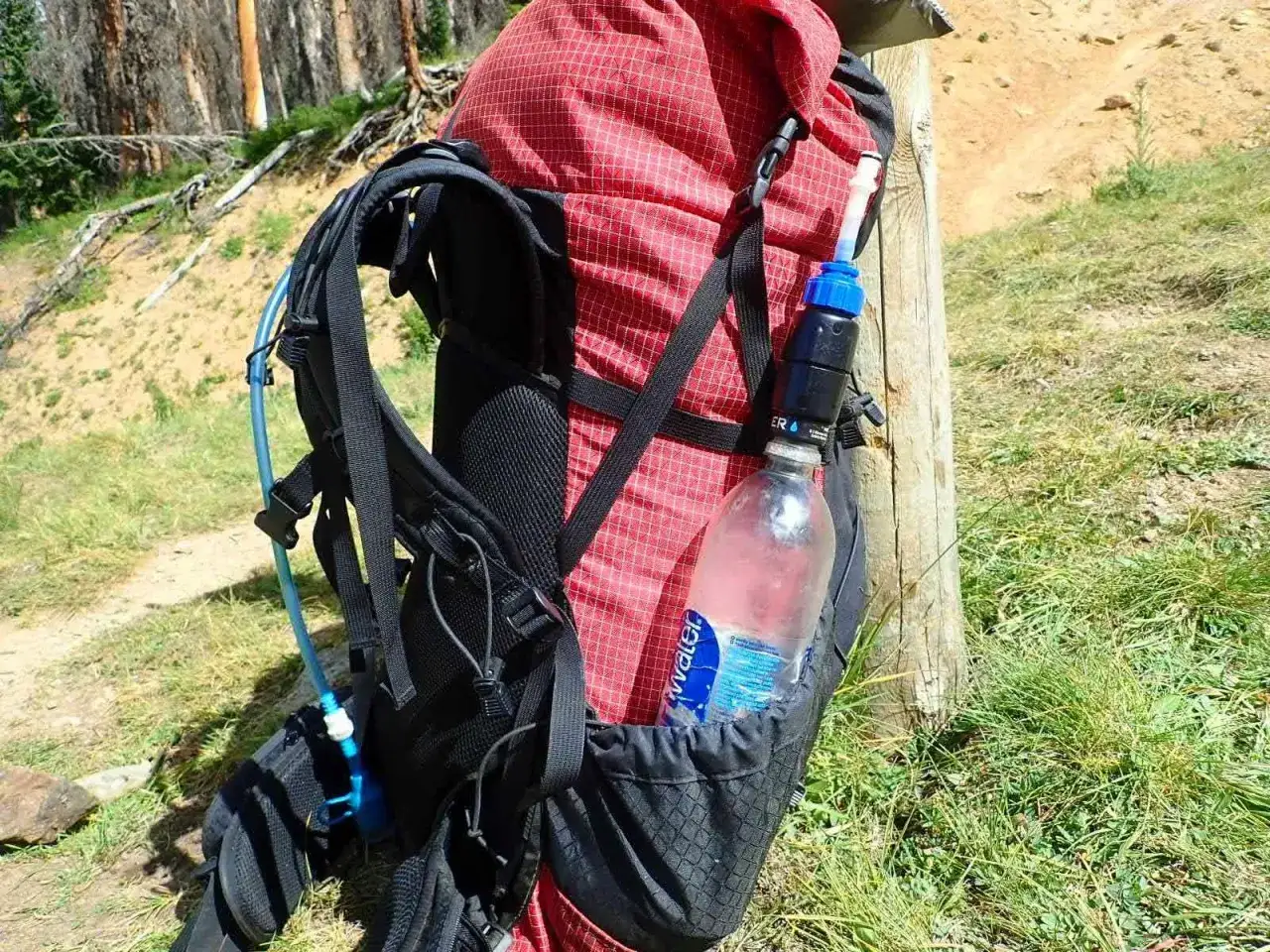 Backpack with a water bottle and filter attached, showing one way how to carry water while hiking.
