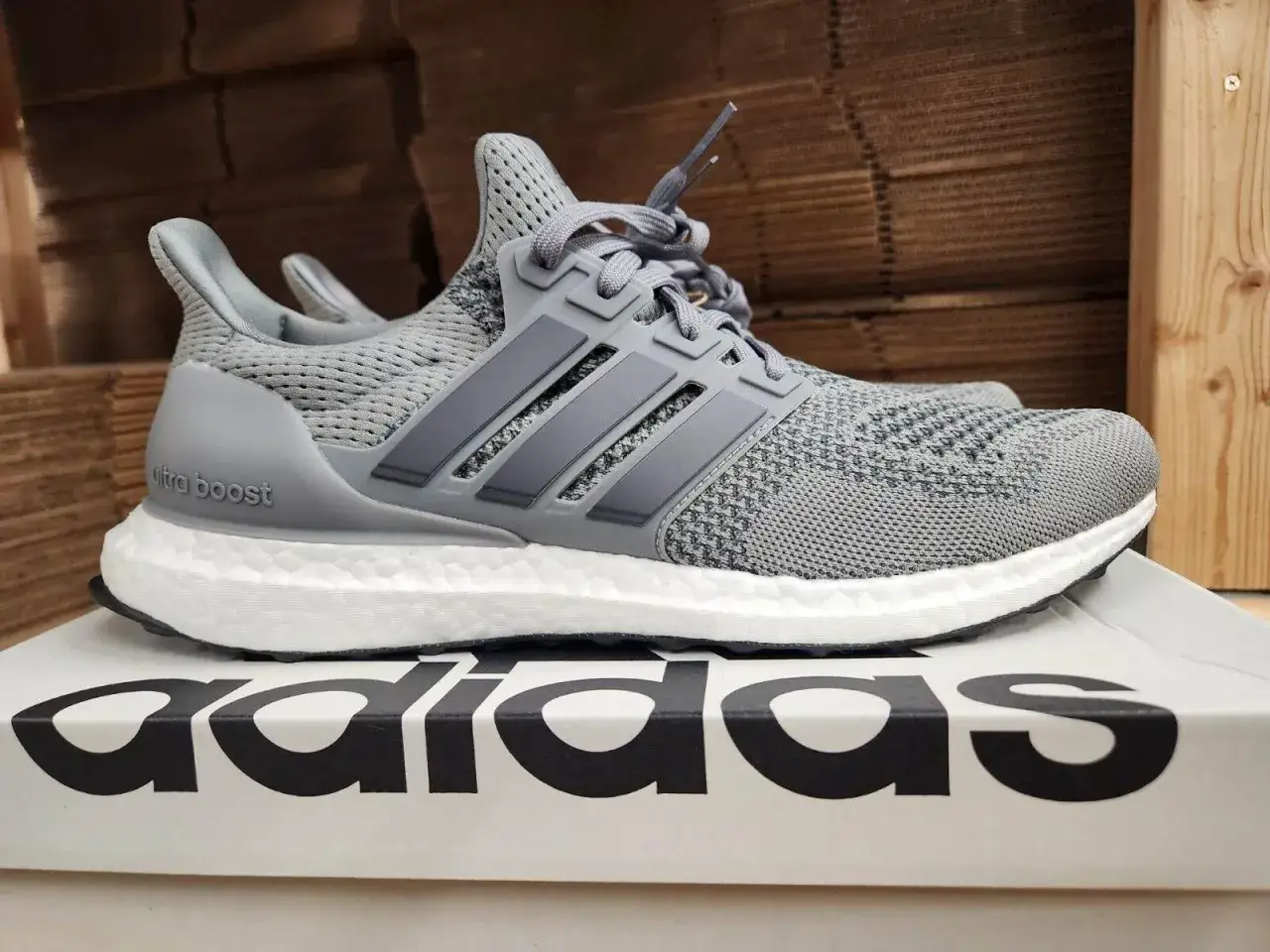 Szare trampki Adidas Ultra Boost, idealne tenisówki do biegania i codziennego użytku, z charakterystycznymi trzema paskami.