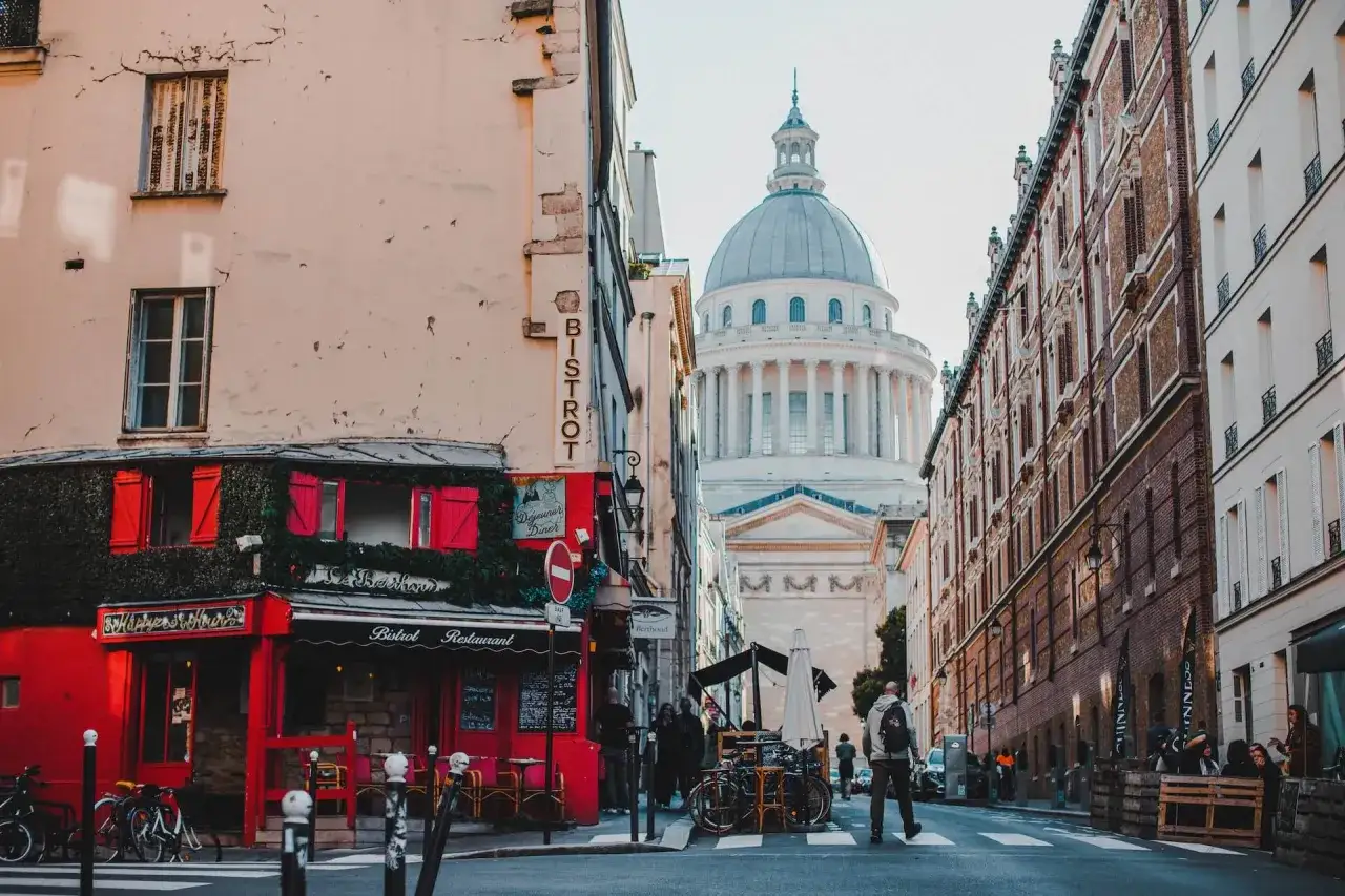 Urokliwa ulica w dzielnicy łacińskiej Paryża z widocznym Panteonem w tle i czerwonym bistro.