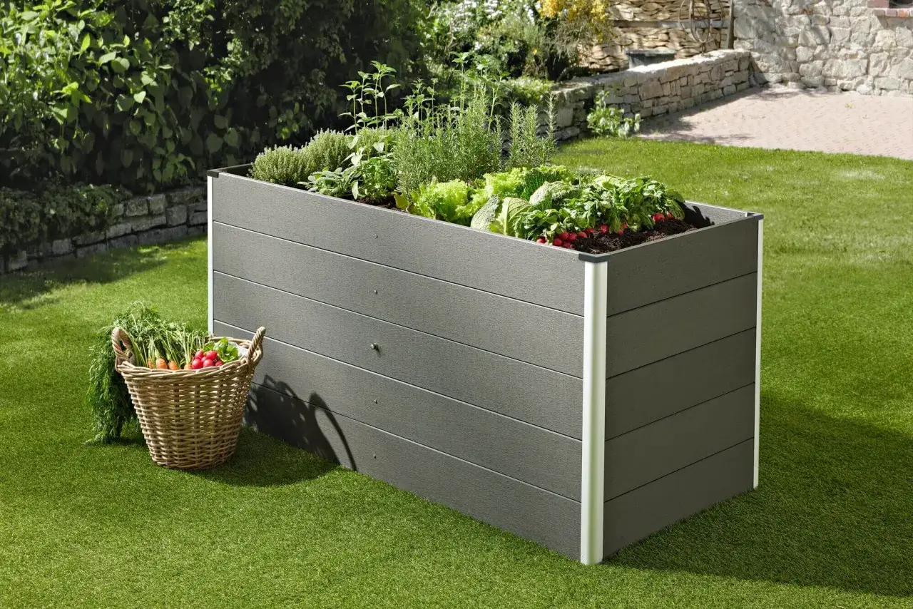 Ein WPC Hochbeet, das einfach selber zu bauen ist, gef&uuml;llt mit frischem Gem&uuml;se und Kr&auml;utern. Daneben ein Korb mit geerntetem Gem&uuml;se.