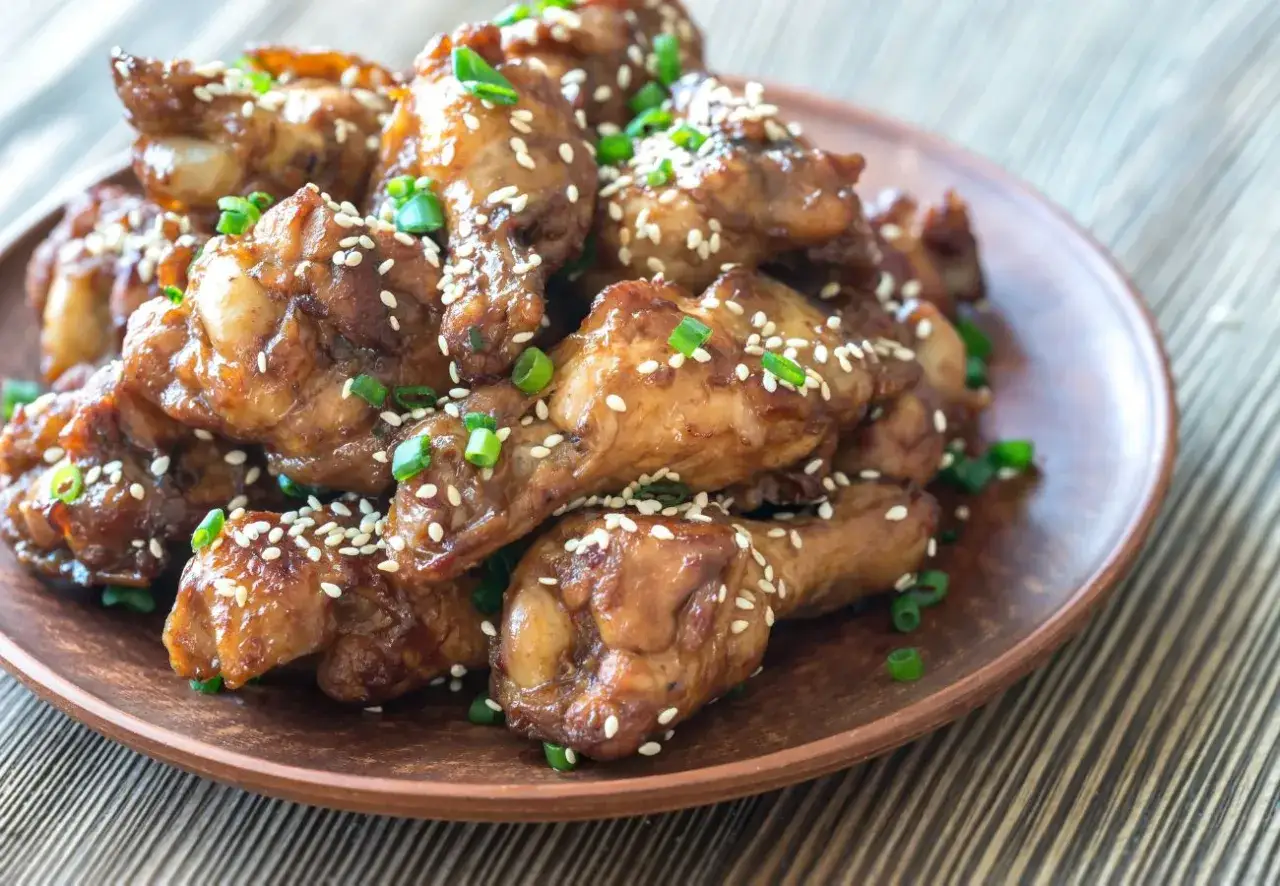 Alitas de pollo glaseadas con salsa de la abuela, espolvoreadas con semillas de sésamo y cebollino fresco. ¡Un manjar irresistible!
