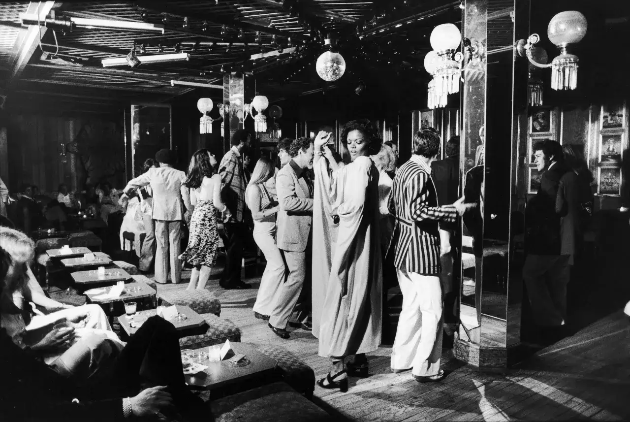 Des gens dansent dans une boîte de nuit, sous des boules à facettes. On se demande qui a inventé le disco en voyant cette scène.