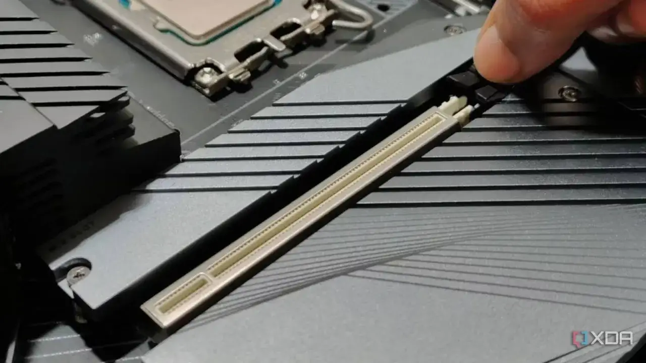 Ein Finger drückt auf den Sicherungshebel eines PCIe 5.0 GPU-Steckplatzes auf einem Motherboard.