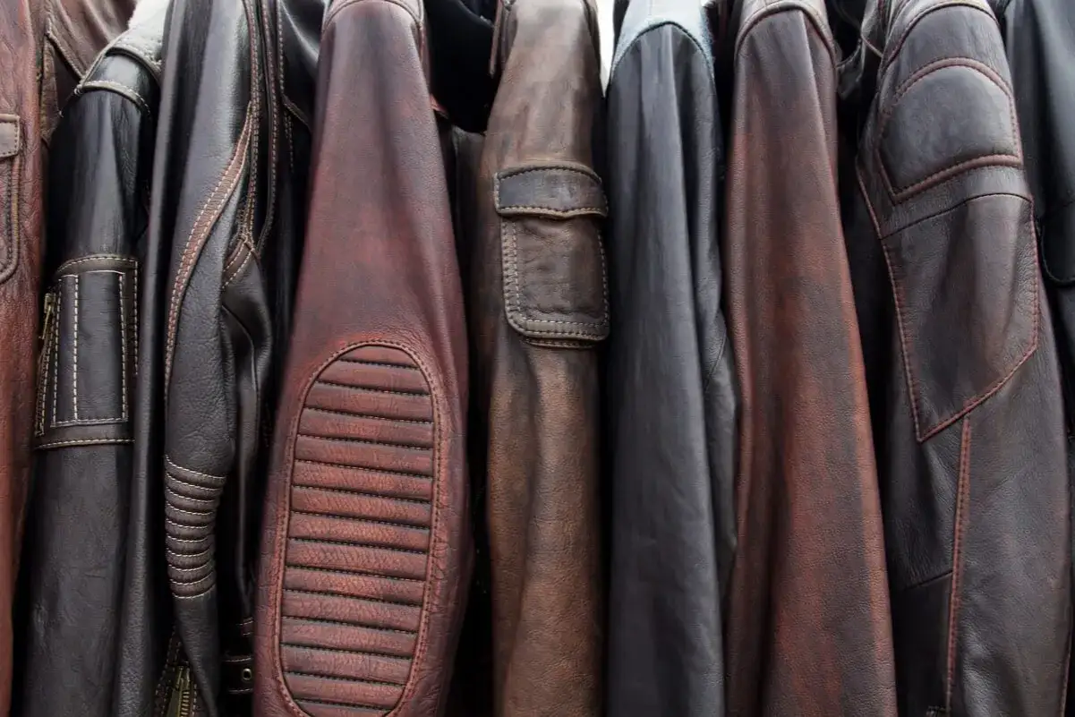 Varias chaquetas de cuero, algunas de ellas Belstaff, cuelgan juntas. El proceso de limpiar Belstaff en casa es clave para mantener su aspecto.