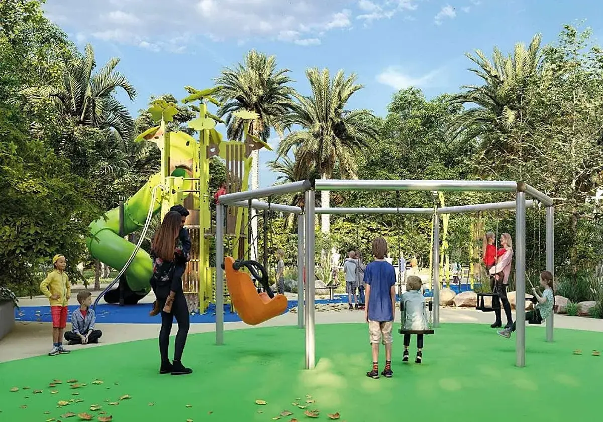 Niños juegan en un moderno parque infantil con tobogán verde y columpios, rodeado de palmeras y vegetación exuberante. El parque el palmeral es un oasis de diversión.