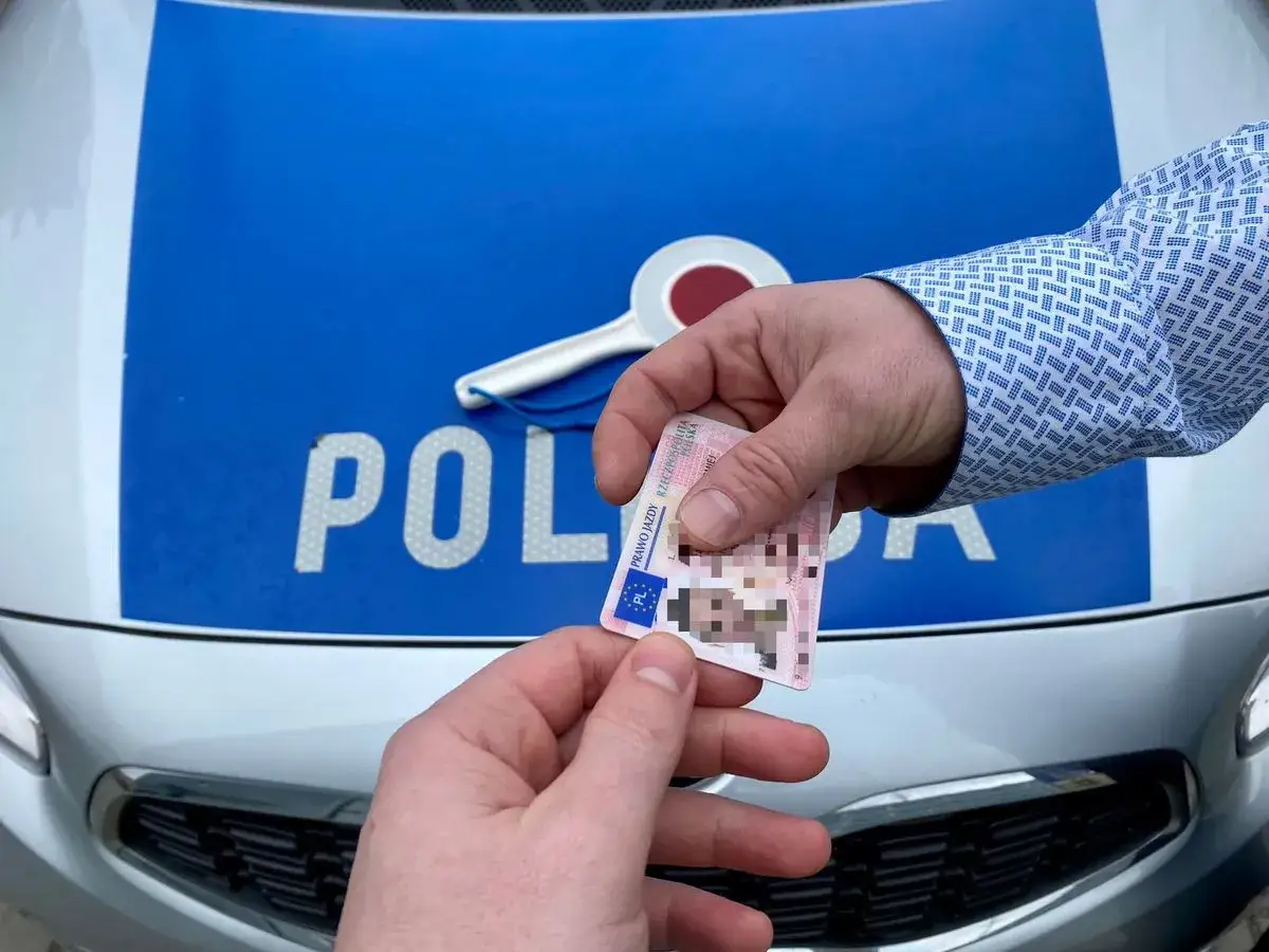 Policjant kontroluje prawo jazdy. To ważny dokument, zwłaszcza w okresie próbnym prawa jazdy.