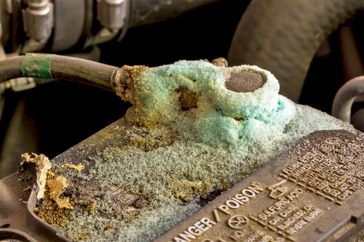 Corroded car battery terminals, covered in green and white powder. This is a sign of a failing battery, raising questions about how long does it take for a car battery to die.