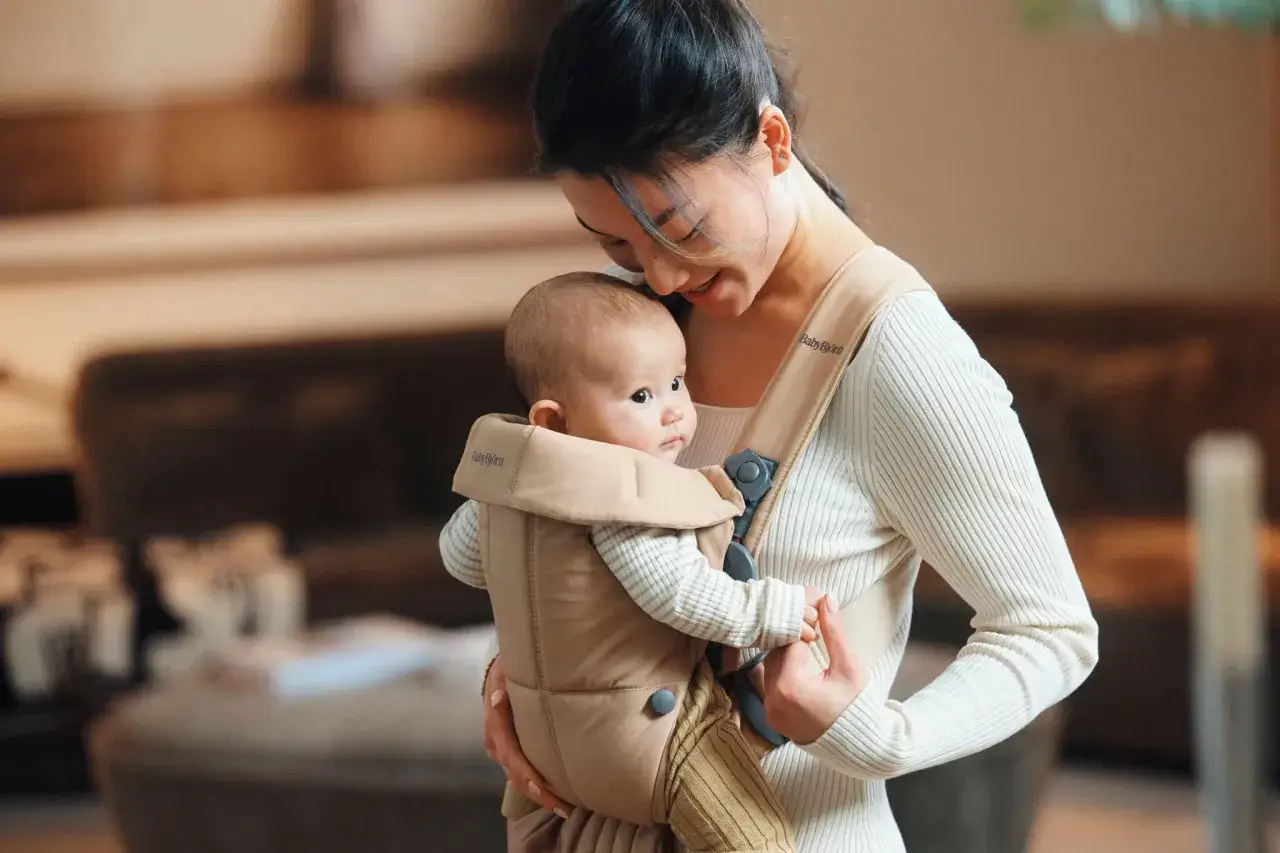 Ciepło i bliskość: mama tuli dziecko w nosidełku BabyBjörn. Od kiedy można zacząć? Od pierwszych dni życia!