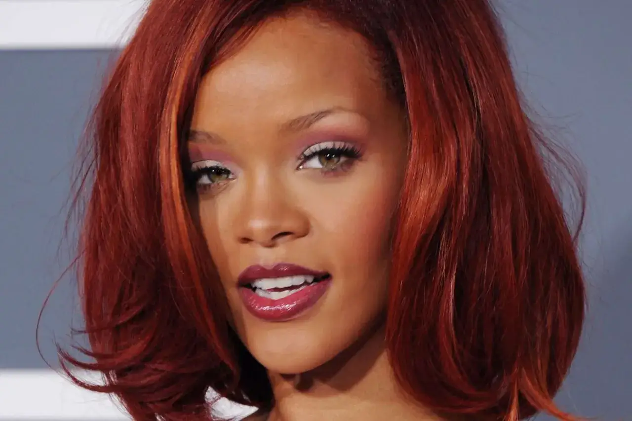 Rihanna z ognistym, rudym kolorem włos&oacute;w i błyszczącymi ustami.