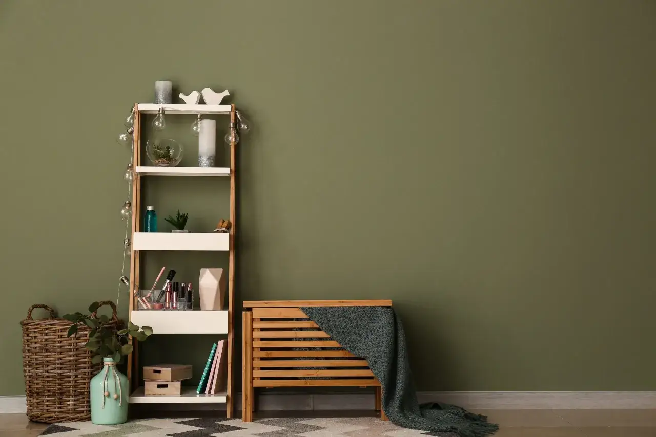 Scaffale bianco con decorazioni, cesto in vimini e un vaso color cachi su un tappeto geometrico.