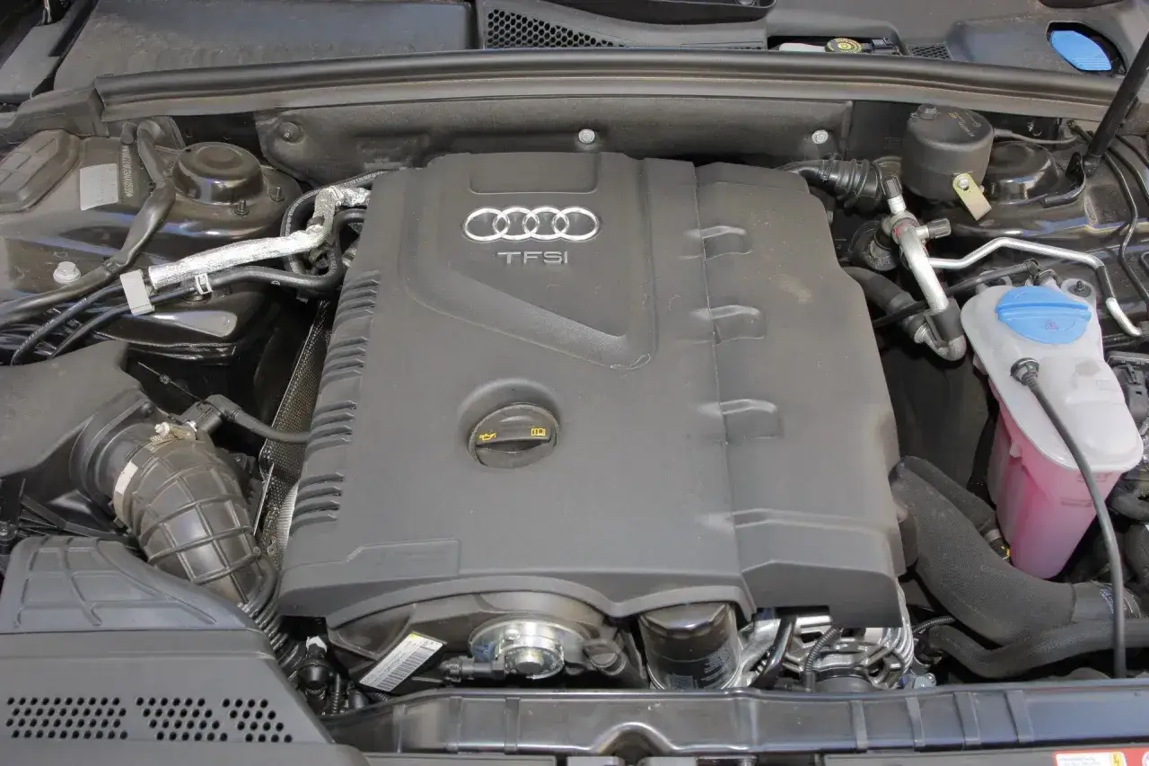 Silnik 1.8 TFSI Audi z widocznym logo i osłoną. Widać elementy układu chłodzenia i dolot powietrza.