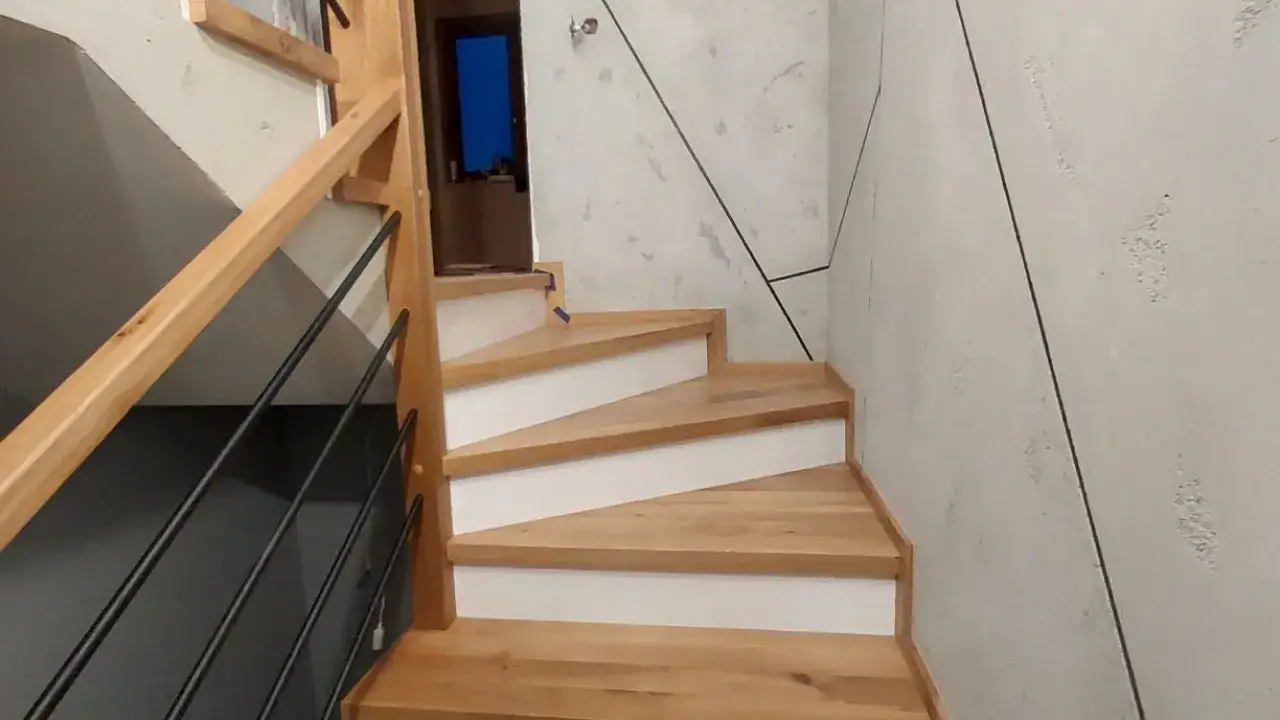 Drewniane schody zabiegowe betonowe z czarną balustradą. Nowoczesne wnętrze z betonową ścianą.