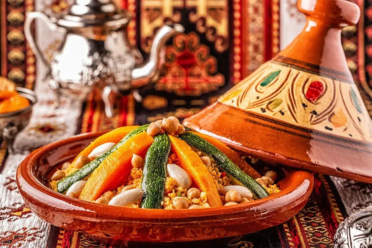 Un plat de couscous coloré avec carottes, courgettes et pois chiches, prêt à être dégusté. Une recette traditionnelle pour un repas savoureux.