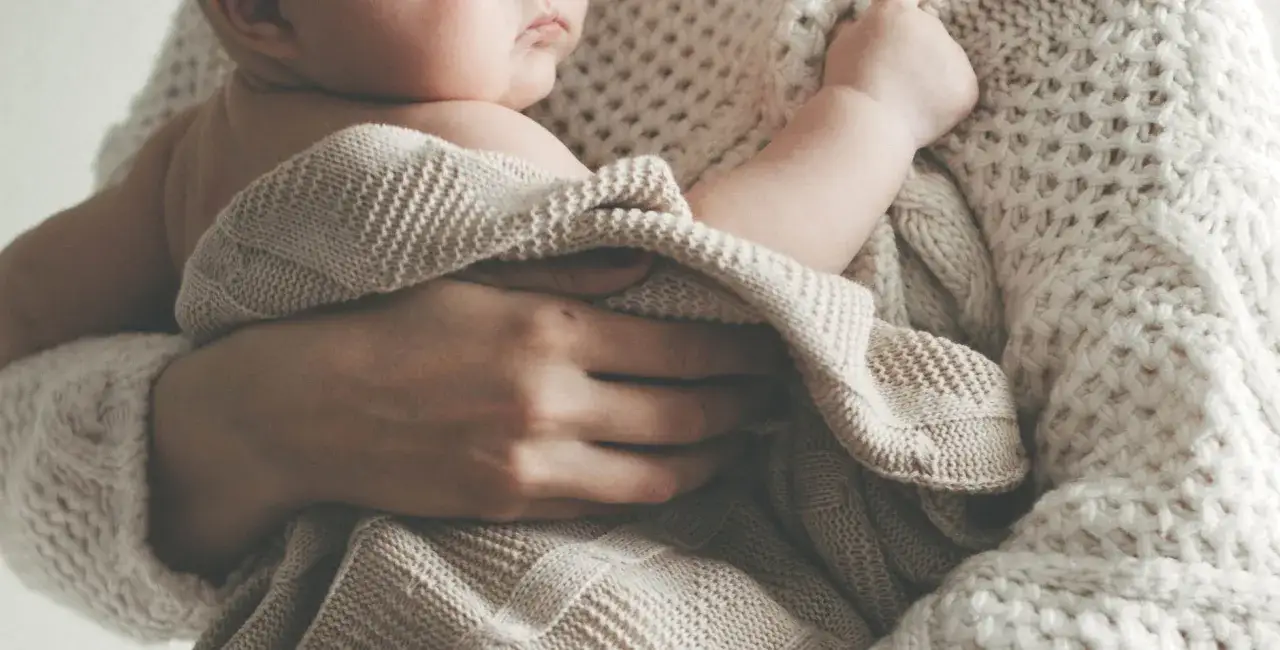 Morbido abbraccio con neonato avvolto in coperte. Idee foto neonati fai da te per ricordi preziosi.
