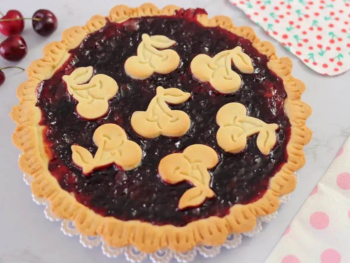 Deliziosa crostata di ciliegie con decorazioni a forma di ciliegia in pasta frolla.