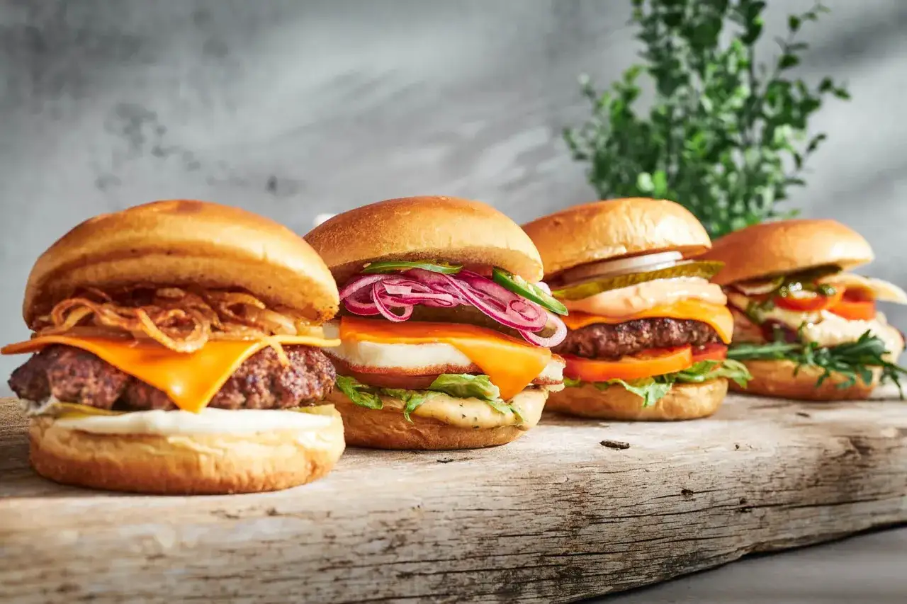 Fyra läckra hamburgare med ost, lök och grönsaker. Ett perfekt hamburgare recept för en festmåltid.