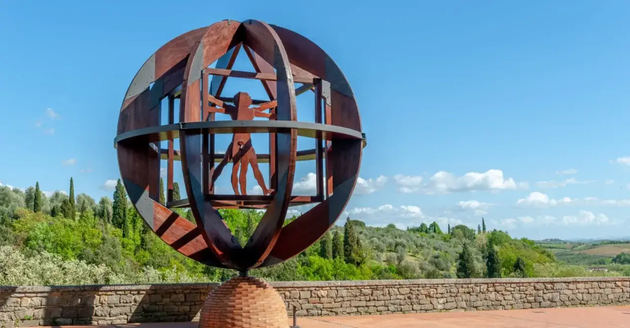 Scultura dell'Uomo Vitruviano nel vinci centro storico, con colline toscane sullo sfondo.