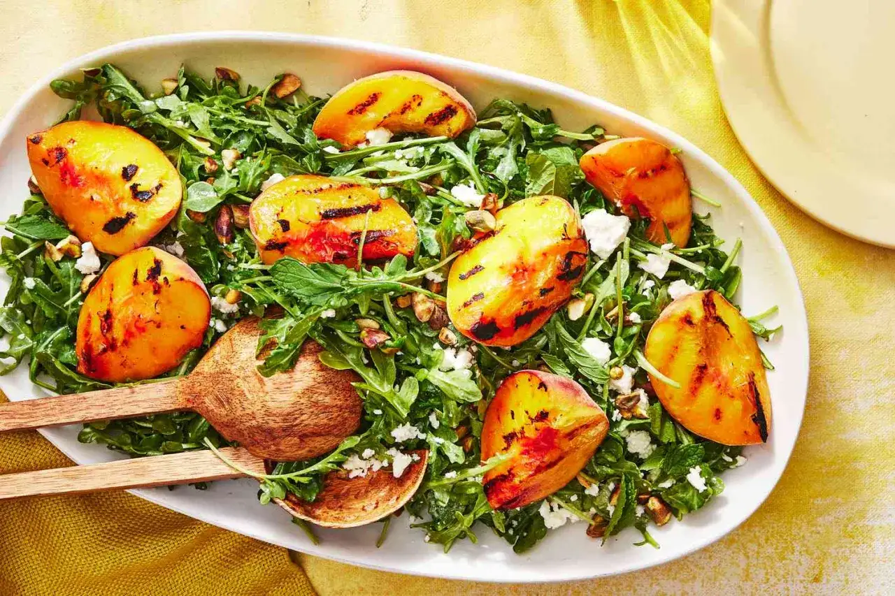 Ein frischer Salat mit Rucola, zerbröckeltem Käse und gegrillten Nektarinen, garniert mit Pistazien. Perfekt für einen leichten Sommergenuss.