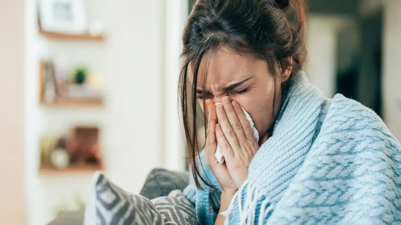 Kobieta z katarem, okryta kocem, chusteczką wyciera nos. Czy to siła wyższa, która usprawiedliwia nieobecność w pracy zgodnie z kodeksem pracy?